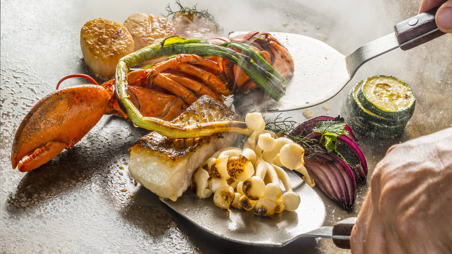 A chef cooks up some teppanyaki on a hot plate