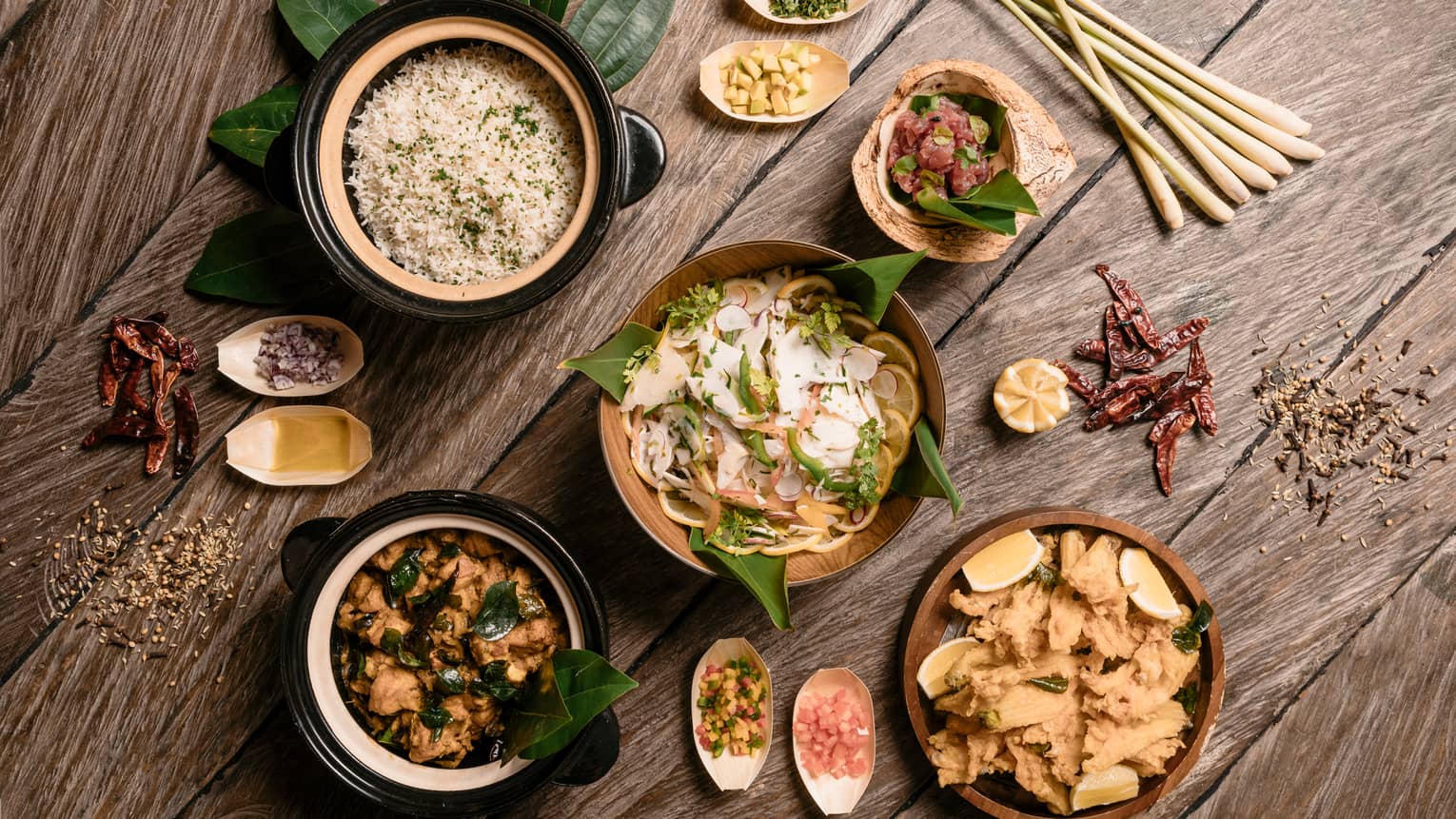 Aerial view of rustic wood table with bowls of gourmet rice, salads and entrees 