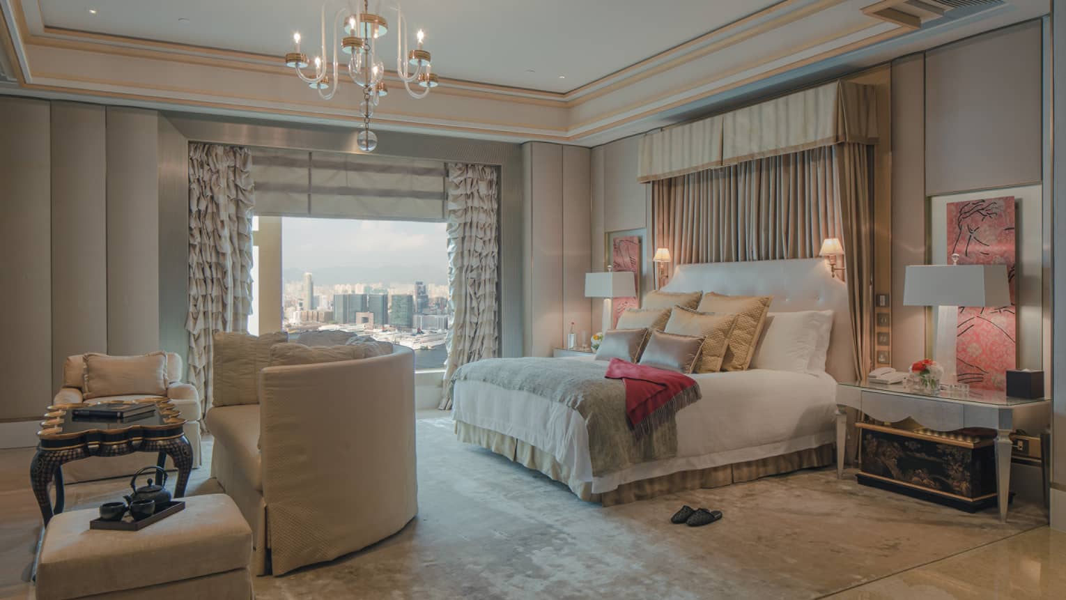 Spacious Hong Kong hotel room bed with curtains above headboard, crystal chandelier, curved loveseat