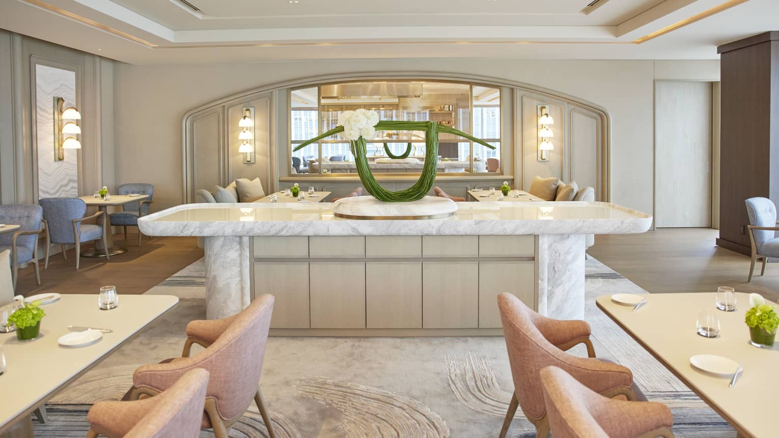 Brightly lit Sezanne with two rectangular tables, peach-coloured armchairs, large marble island in the centre