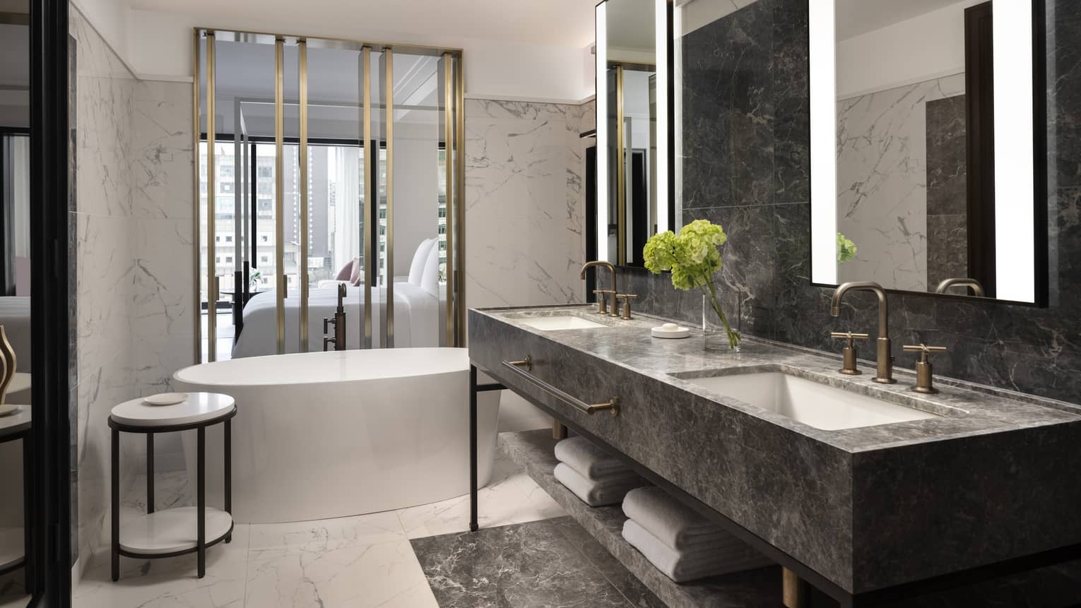 A marble bathroom with a double sink and large circular marble tub