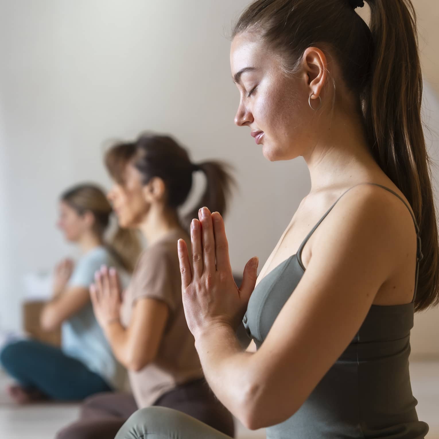 A guest with their hair in a ponytail practicing yoga with other guests