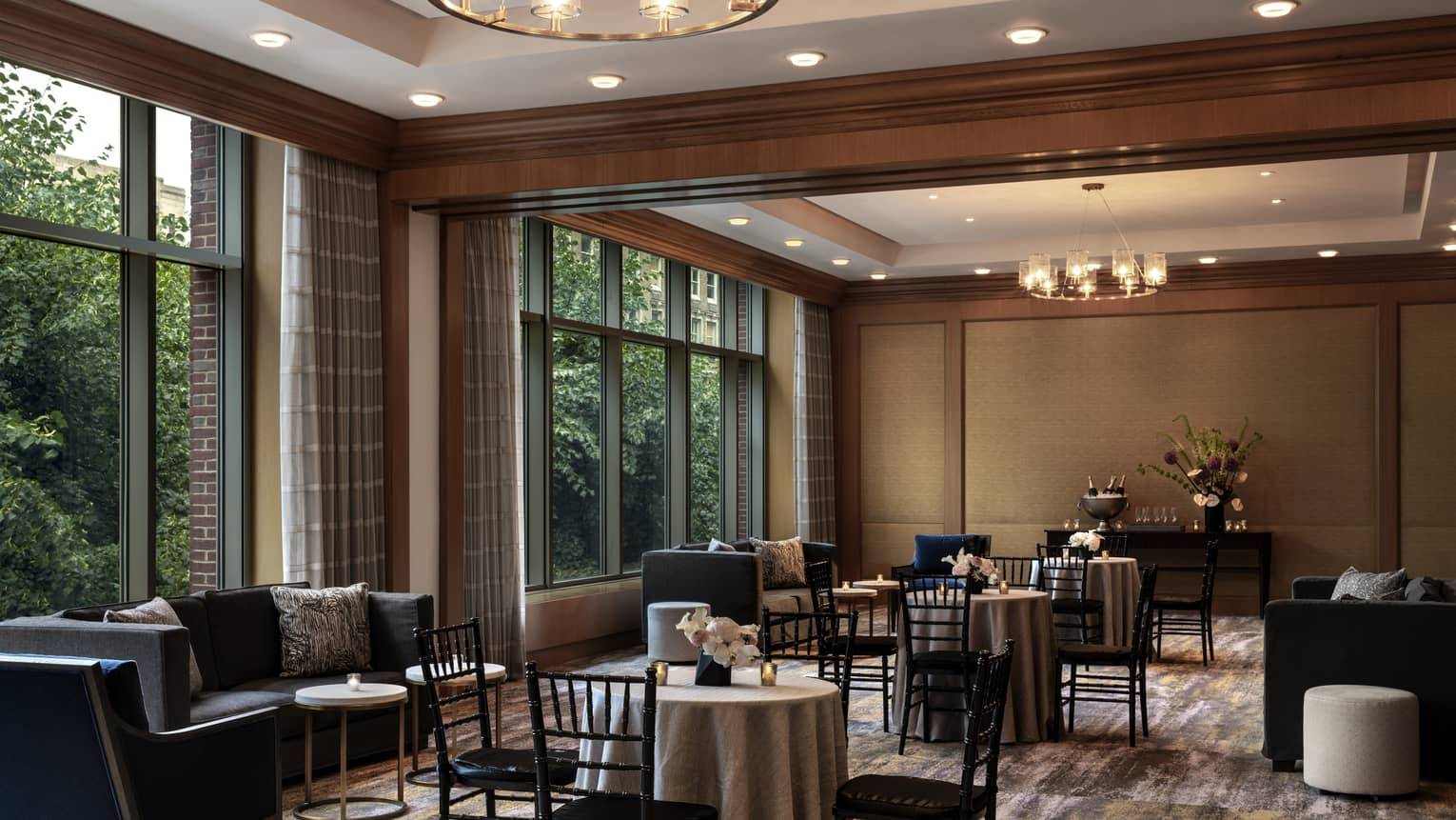 A  dimly lit seating area with black chairs around small tables and small black sofas.