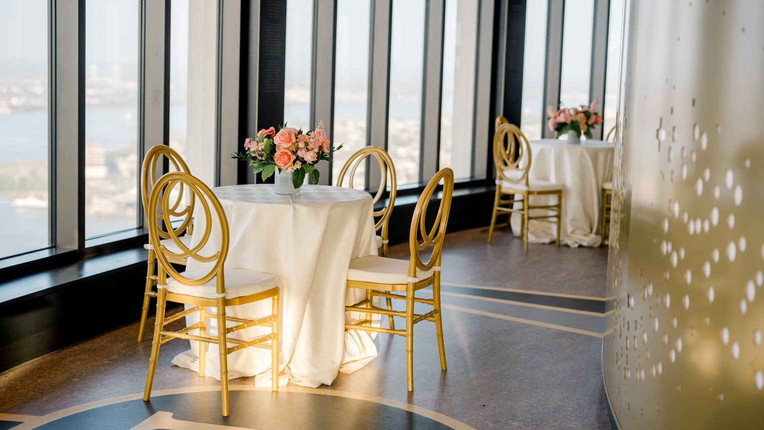 A small table with a white cloth near large windows on a high floor.