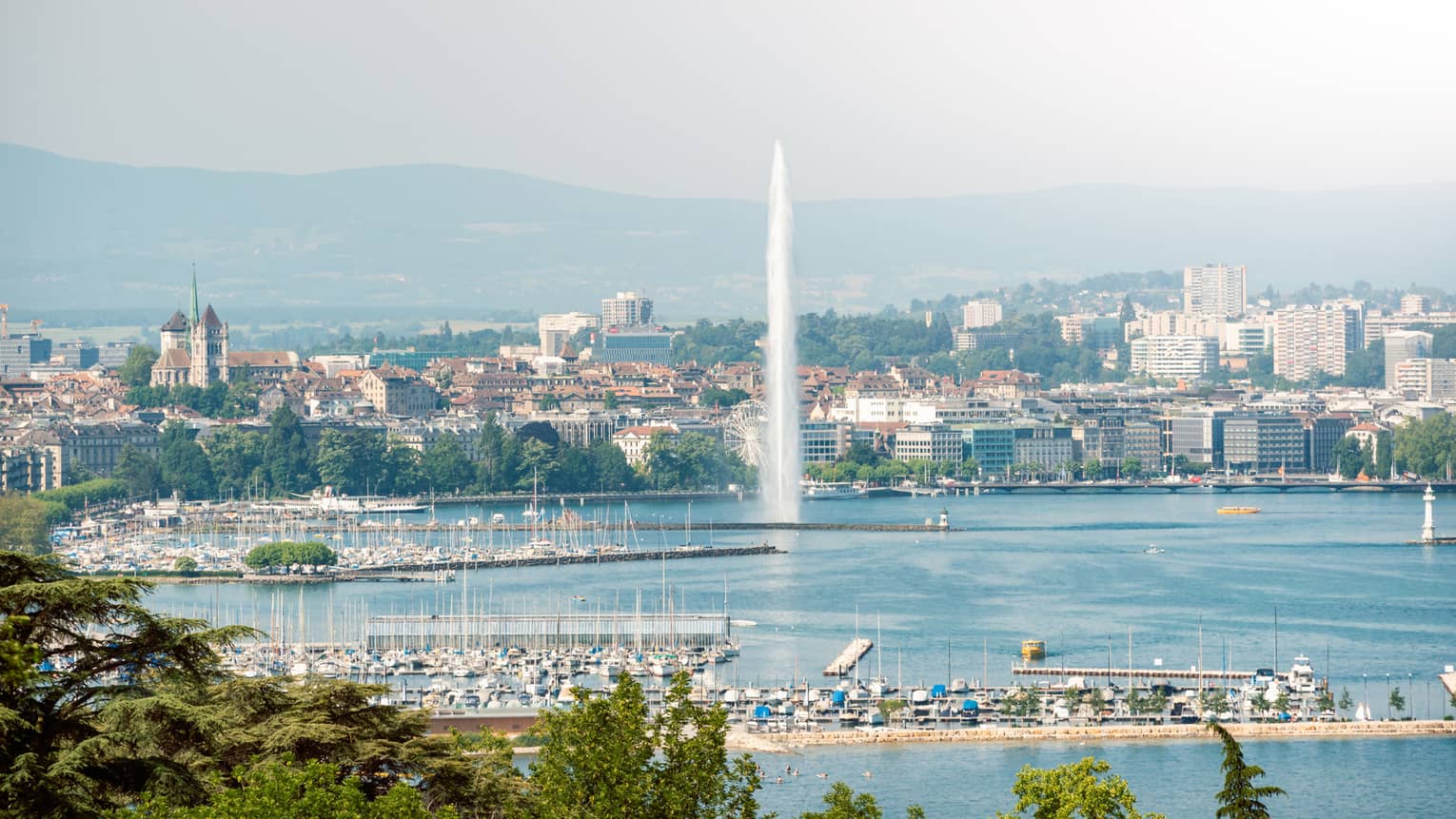 Lake Geneva's Jet d'Eau with city and mountains in backdrop