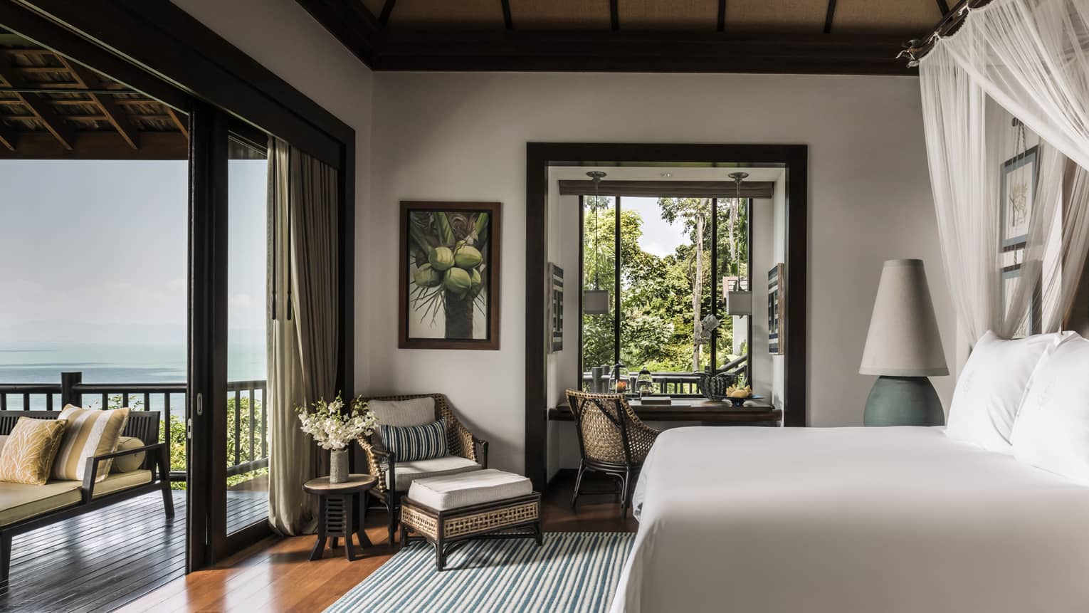 Deluxe One-Bedroom Pool Villa bedroom with bed, wicker armchair, open-air wall to patio