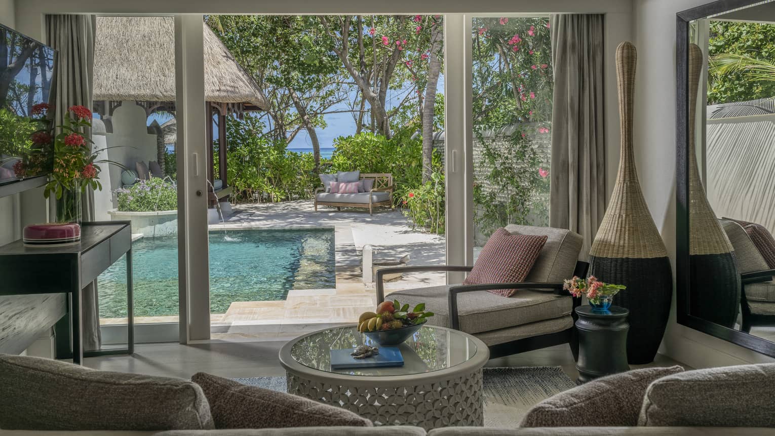 Living room opening to pool deck, with beach in the distance