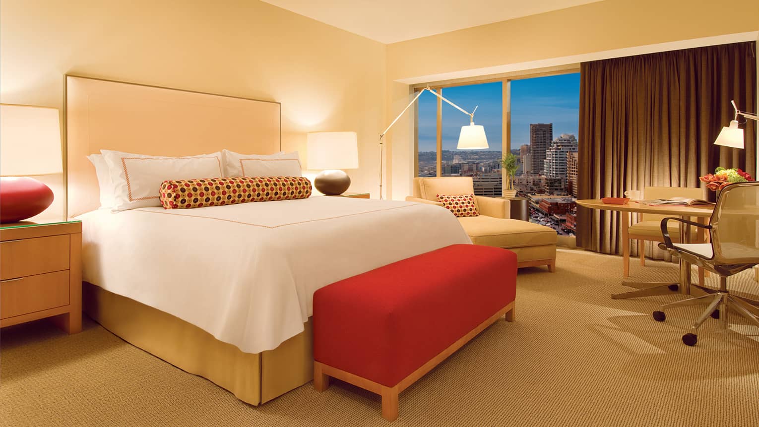 Deluxe Seattle-View Room bed with plush red bench, beige chaise in front of window, urban view