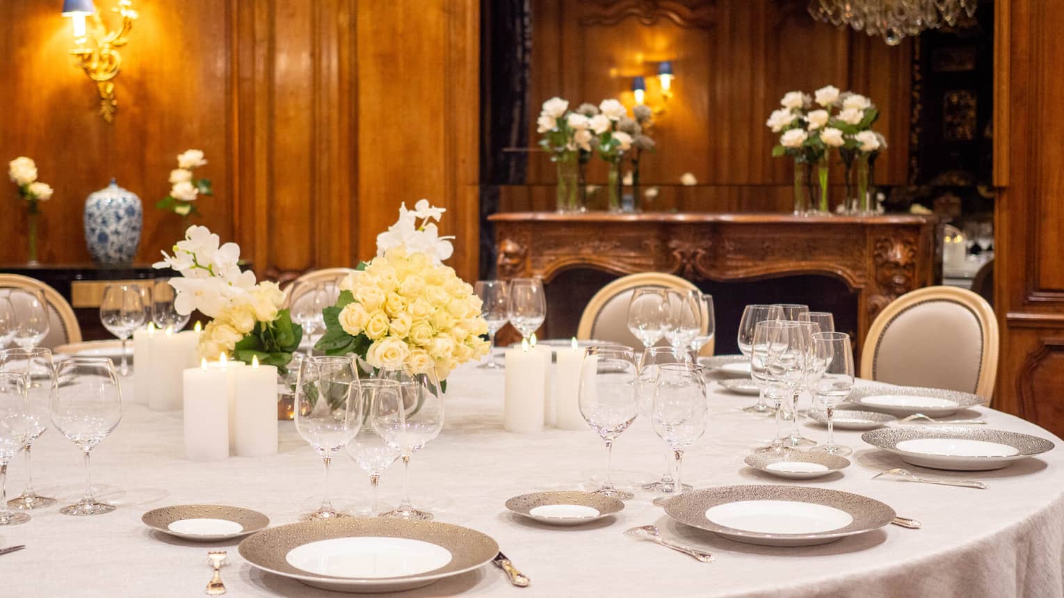 A dining table set with plates, wine glasses and floral arrangements in a private dining room