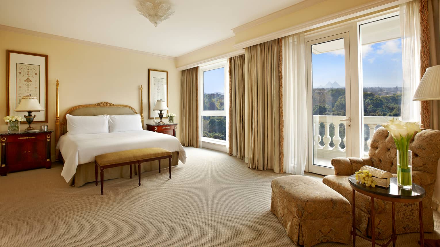 Spacious Ambassador Suite bedroom with bed, bench, glass patio doors to white pillar balcony