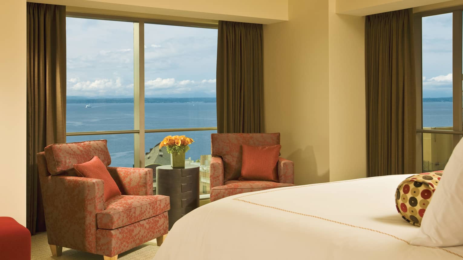 Corner Elliott Bay Suite foot of bed, two red armchairs in front of corner windows