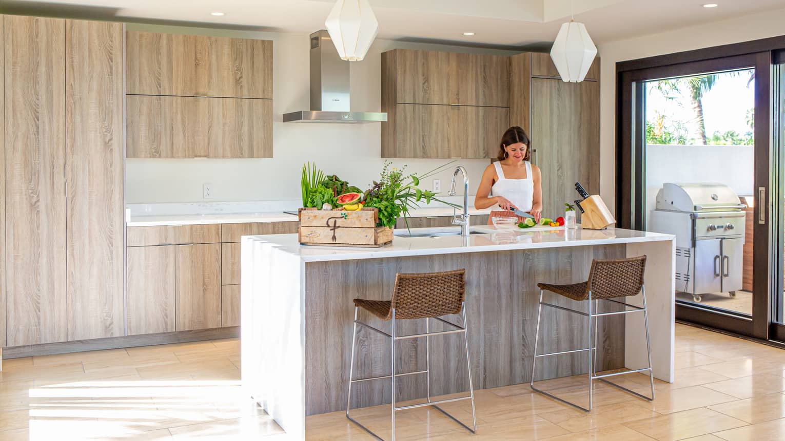 Interior of villa kitchen with woman chopping vegetables