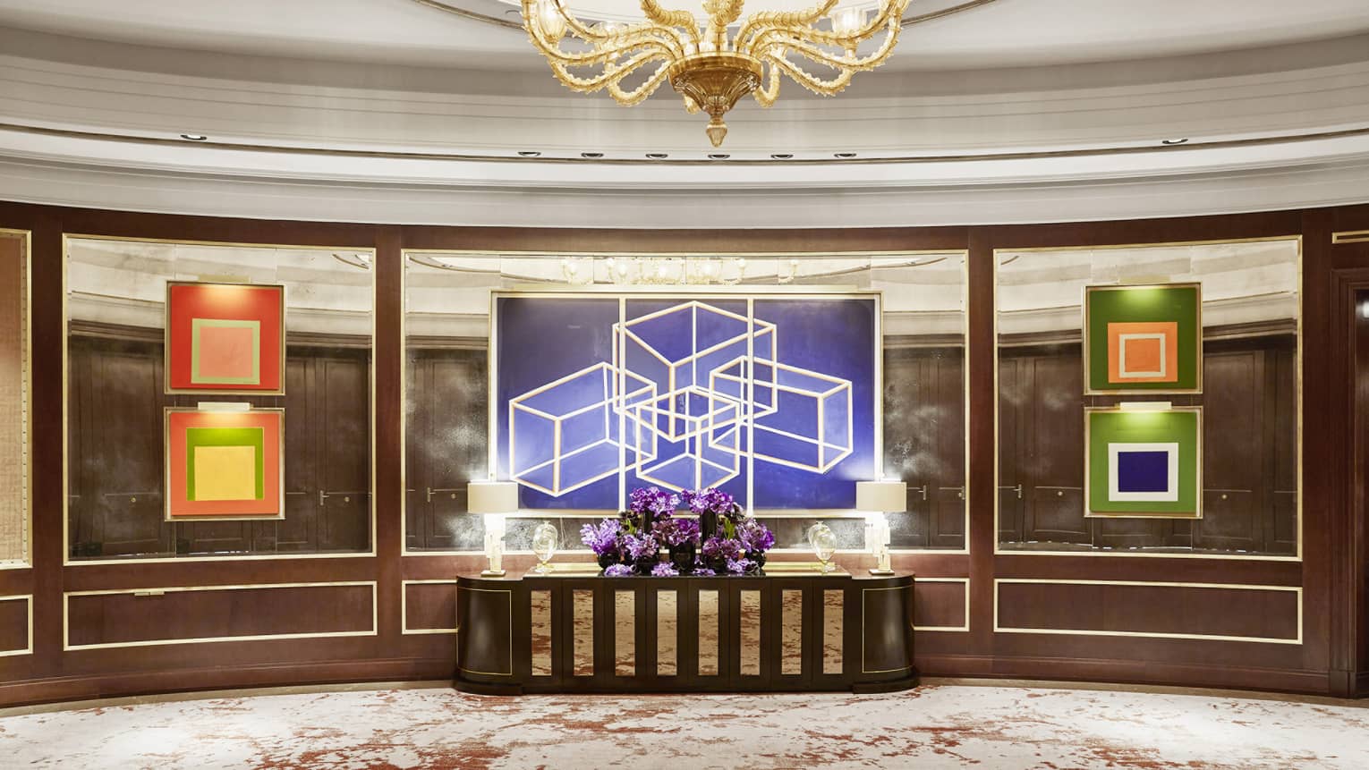 Sol Foyer with mirrored walls, colourful artwork, centre table with purple flowers, gold chandelier