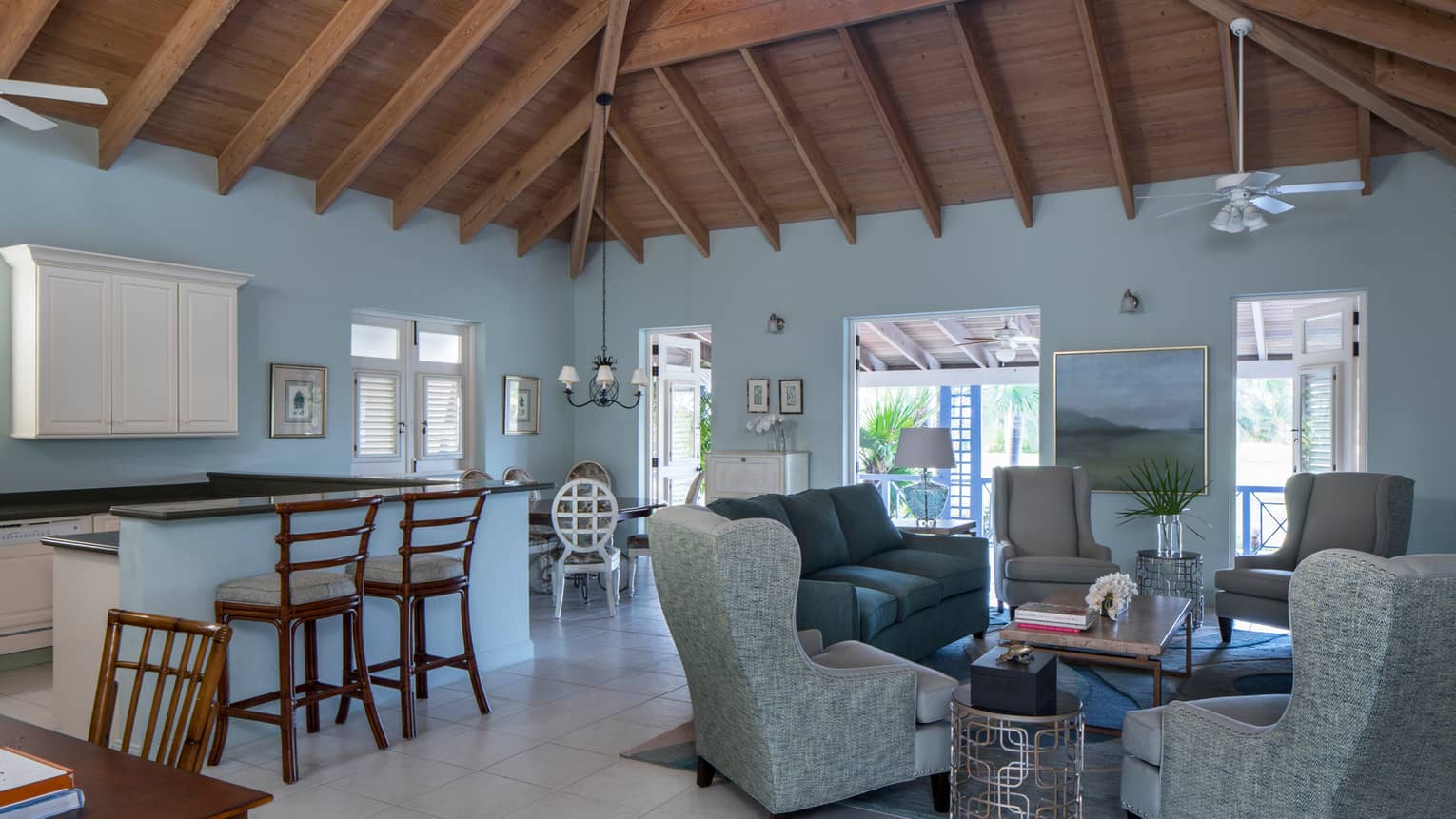 Kitchen island with stools, living room with sofas, armchairs under thatched roof ceiling