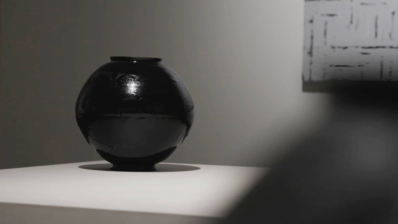 A large black circular art piece casts a dark shadow on a white table