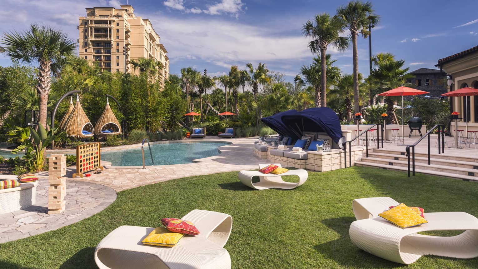 White patio chairs, hanging baskets, palm trees around swimming pool deck