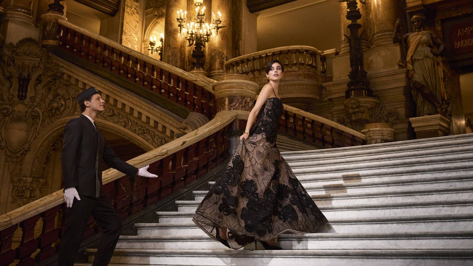 A woman in ballgown ascends grand staircase of opera