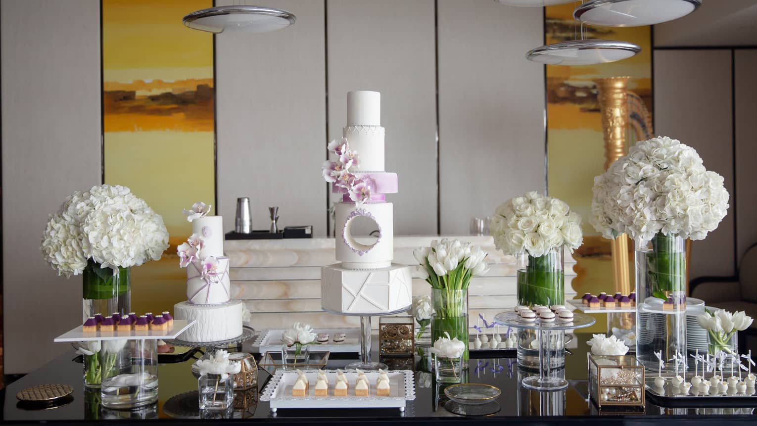 Wedding cake and dessert display with white roses in vases
