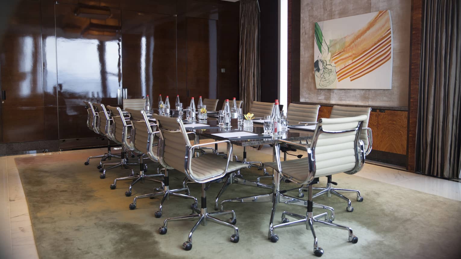 Meeting room with boardroom table, white leather swivel chairs and modern art painting