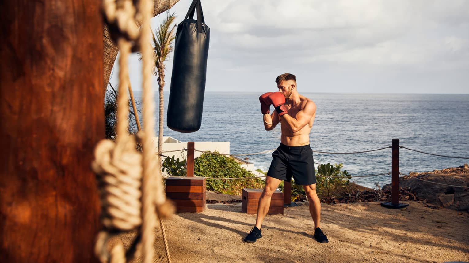A guest engaged in a boxing session, perched above a cliff overlooking the Pacific Ocean