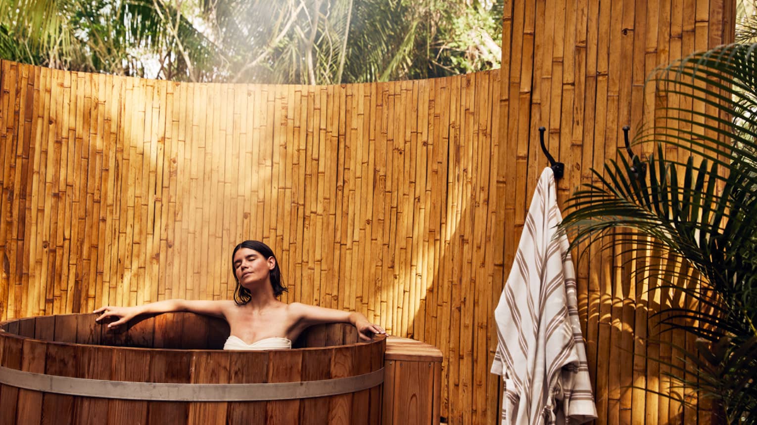 A woman in a wooden tub outside.