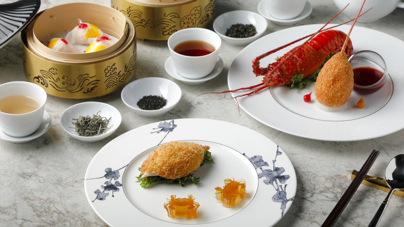 Plain white cups of tea are surrounded by bowls of dried tea leaves, baskets of dumplings and plates of lobster and seafood.
