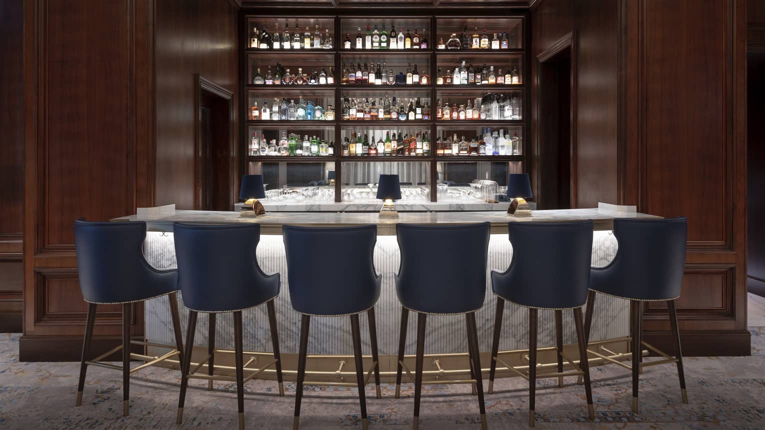 A marble bar with blue stools and wood walls.