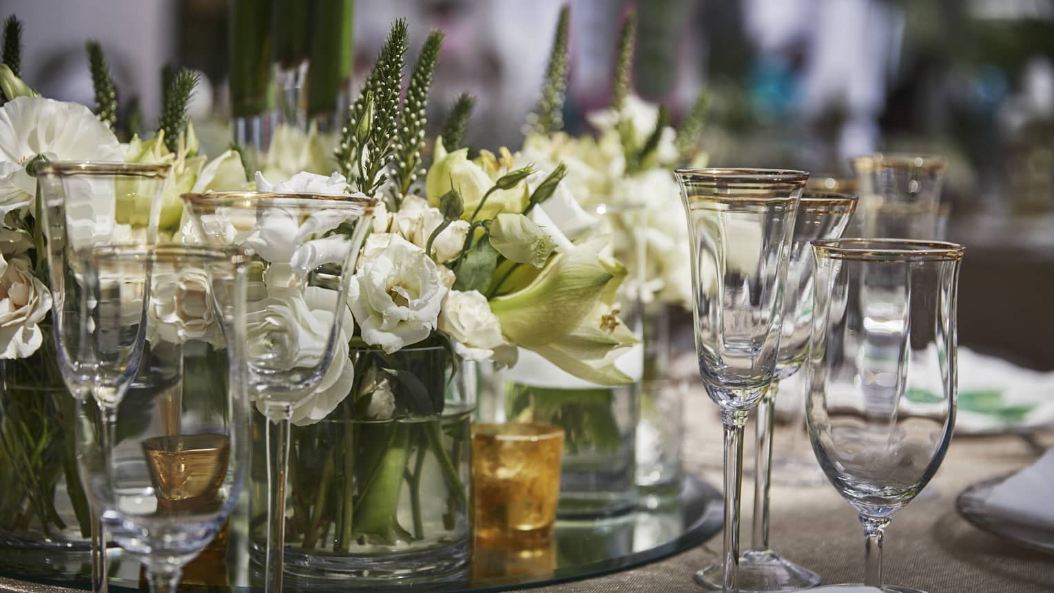 Various glass goblets are arranged with candles and white flowers 