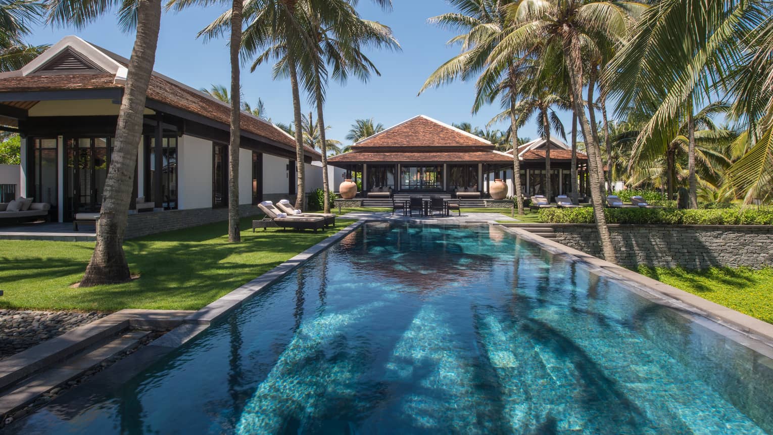 Two-Bedroom Pool Villa exterior at end of long outdoor swimming pool, lawns