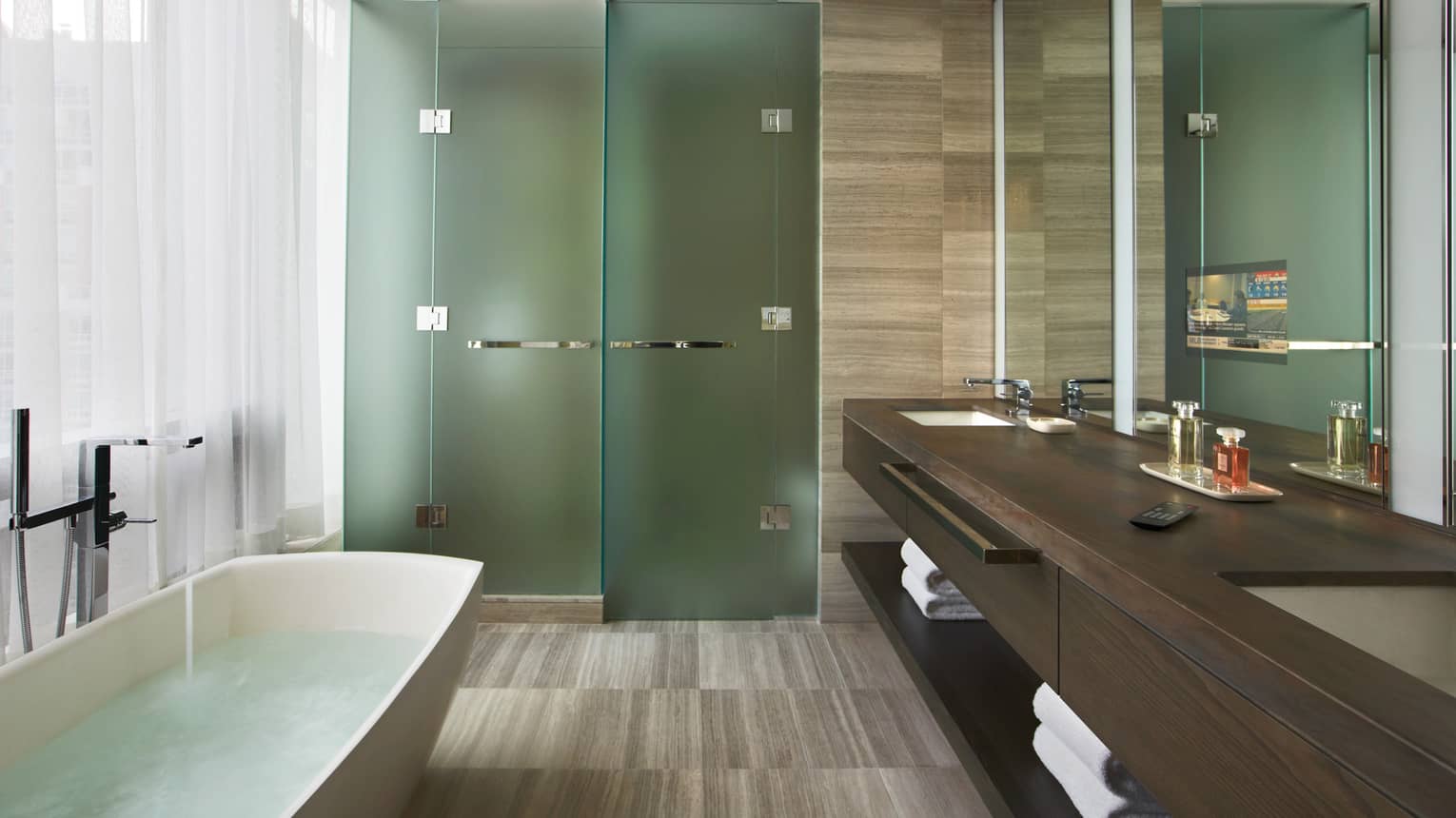 Granite bathroom with freestanding tub, glass rain shower and double wood vanity