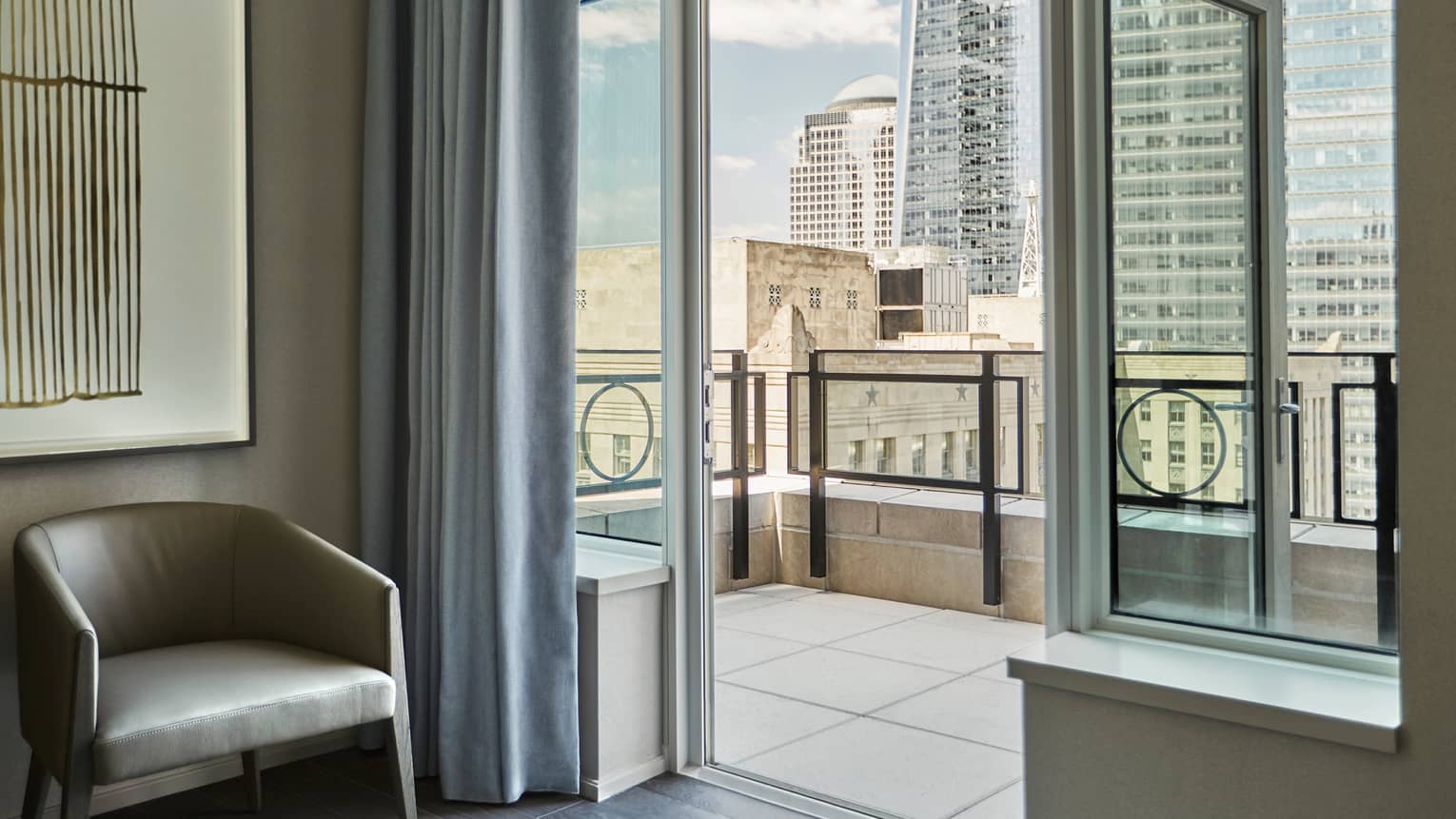 Tribeca Suite leather mid-century style chair by open door to tile balcony overlooking downtown New York