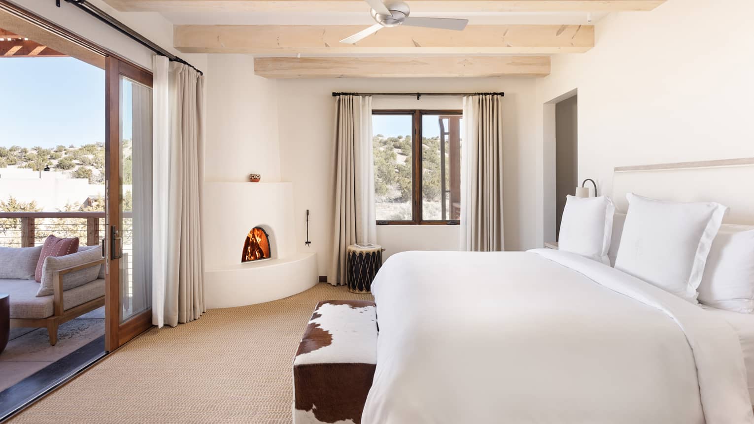 Guest room with king bed, cowhide bench, fireplace and terrace