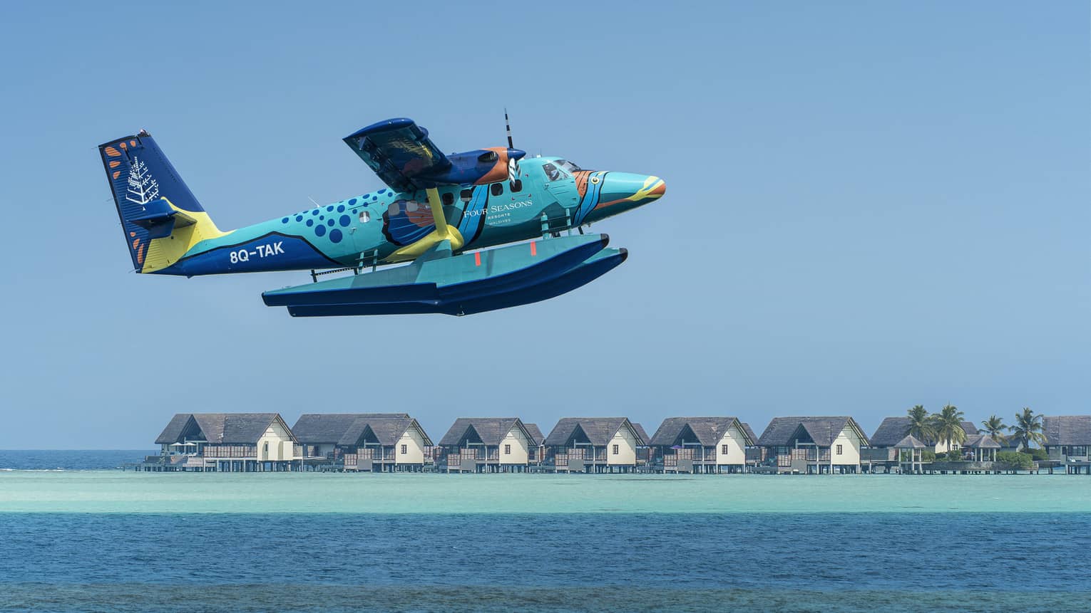 Maldives Sea Plane taking off with water villas and palm trees in the background