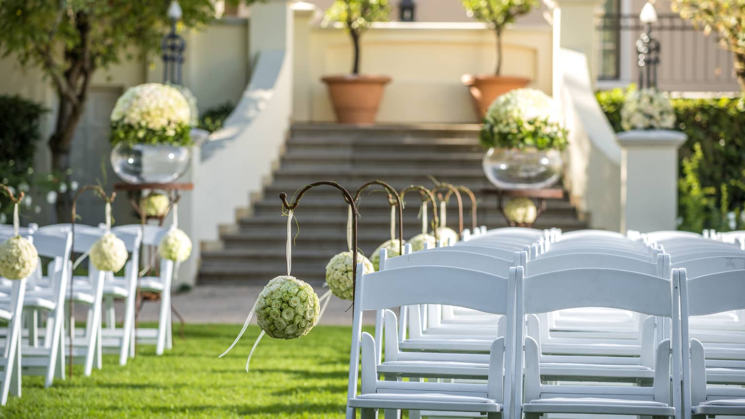 Close-up of white chairs in rows on green Rose Garden lawn for wedding ceremony