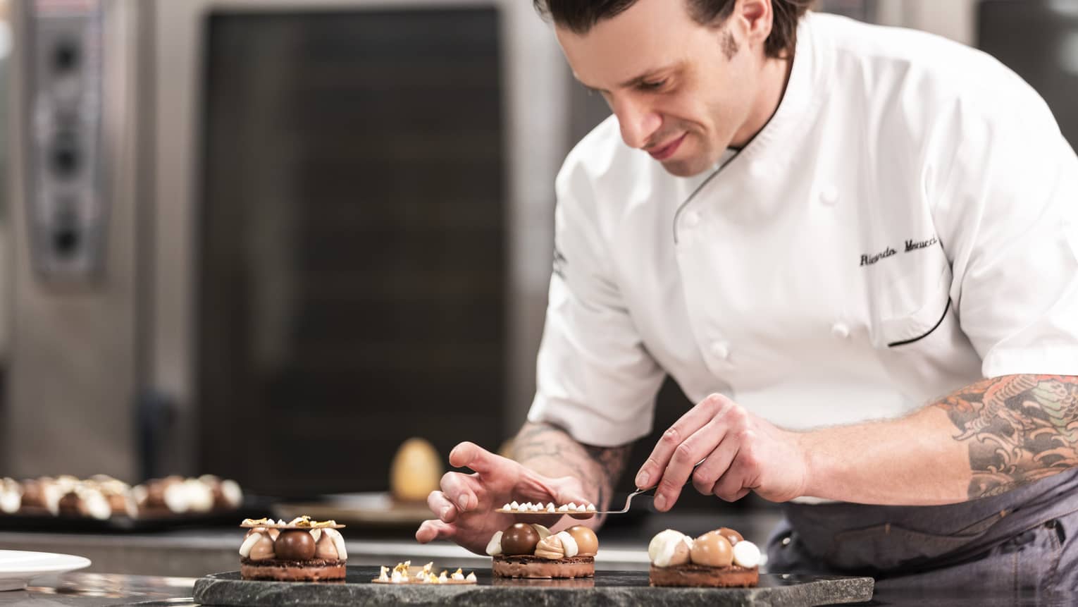 A chef in a white chef's coat making desserts.