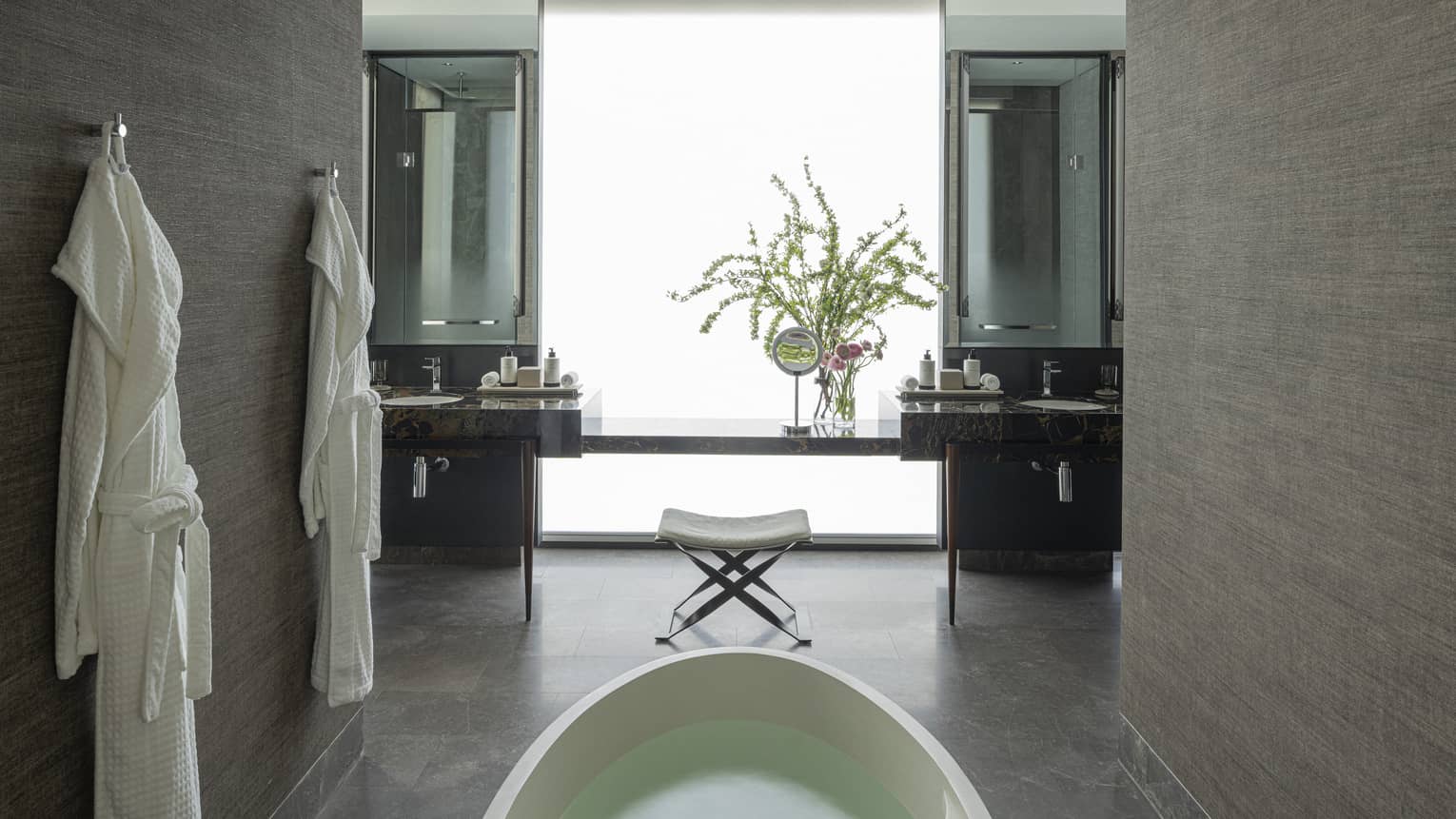 Luxury bathroom with standalone tub and two hanging bathrobes