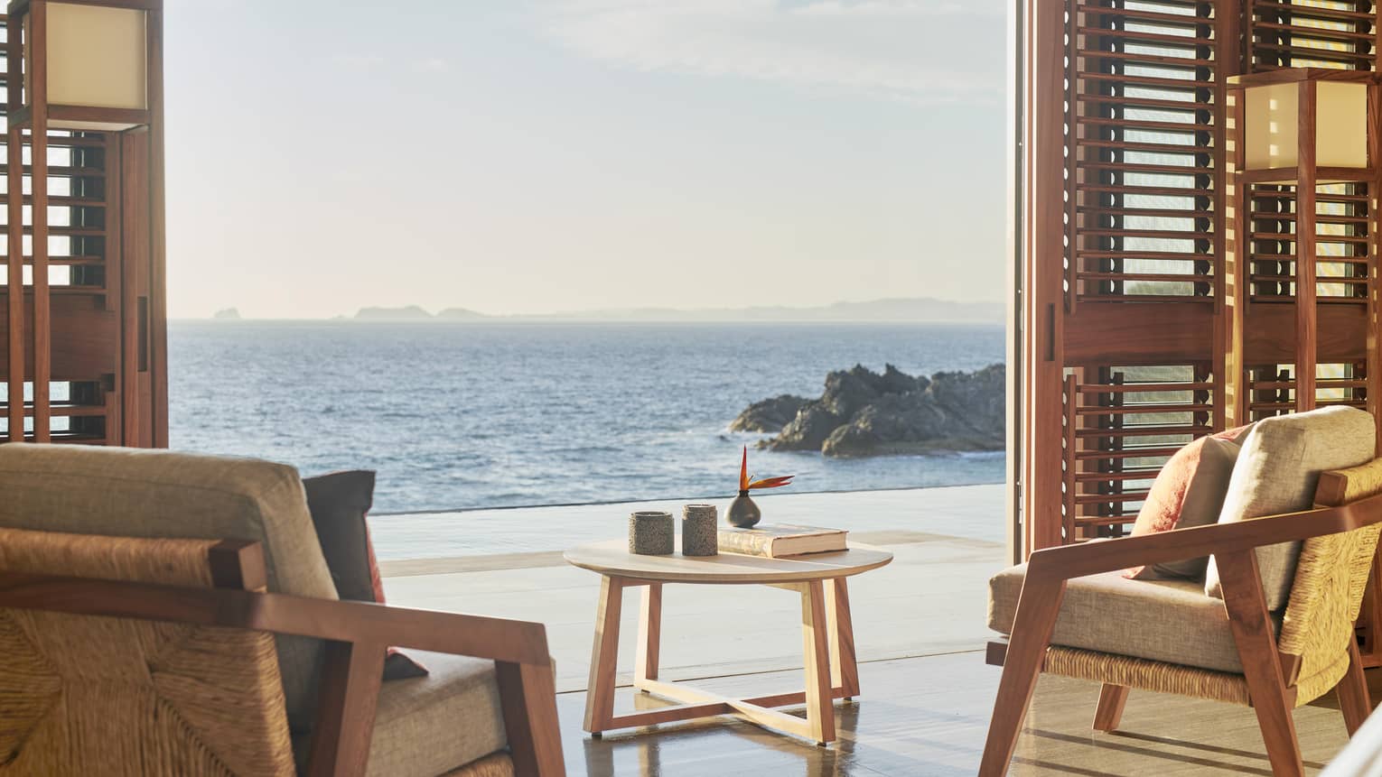 Resort bedroom sitting area, with shutter doors opening to ocean-view terrace
