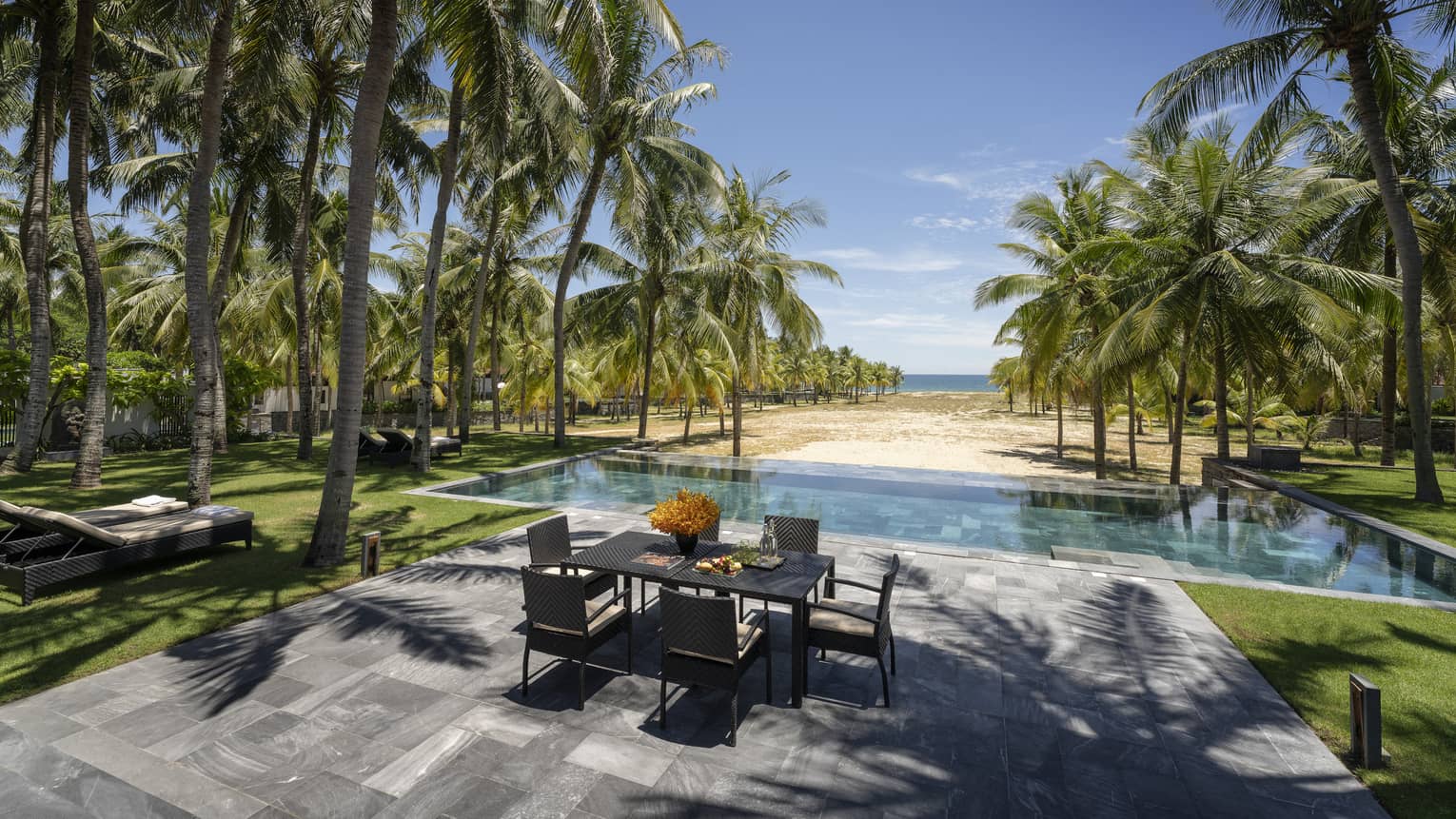 Three-Bedroom Pool Villa pool area with dining table, lounge chairs, palm trees, ocean views