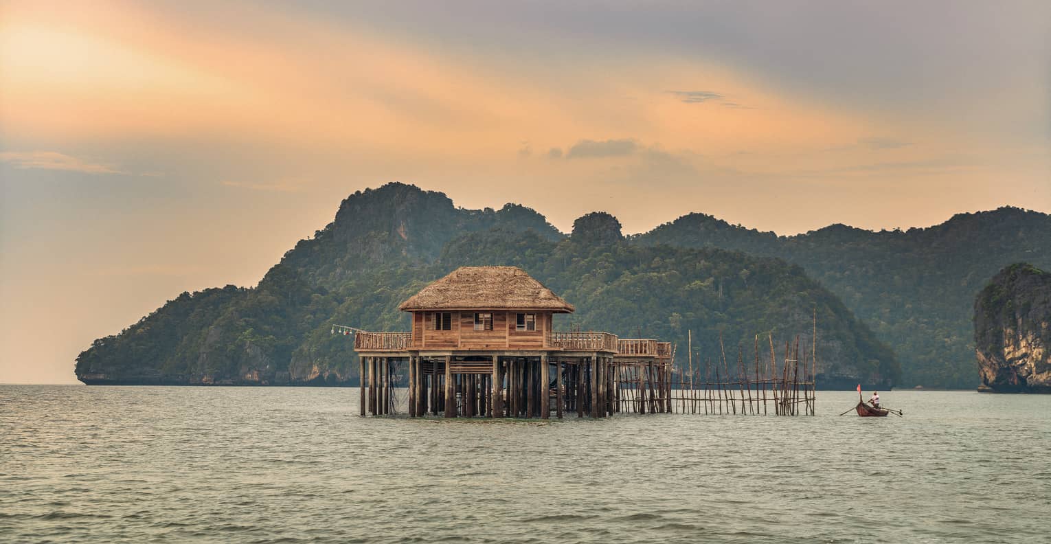 A sunsetting over a lake with huts on it in Langkawi 