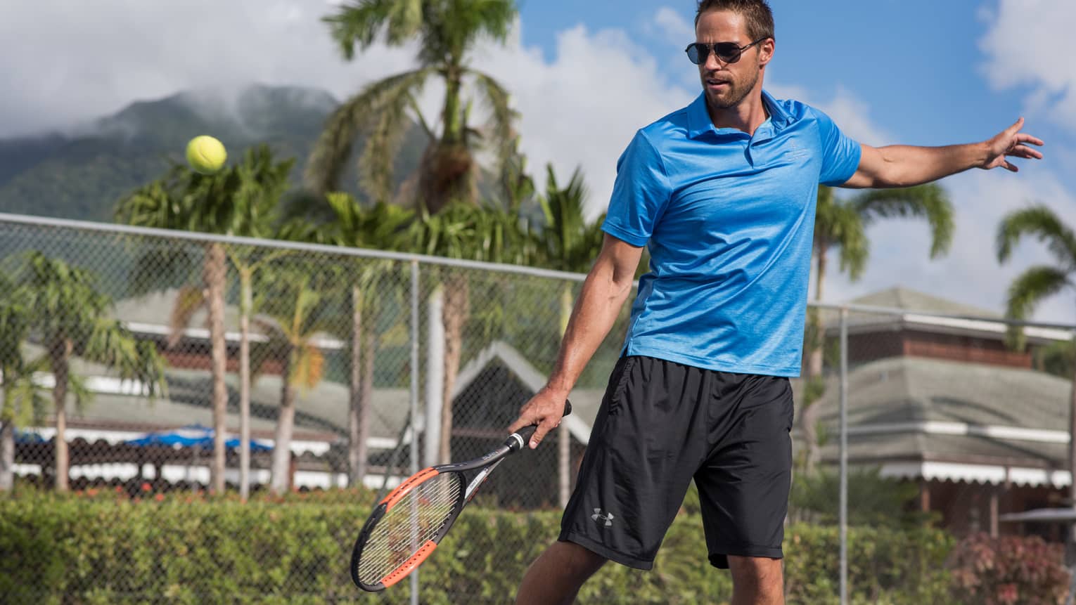 Tennis ball in air, man swings racket on court
