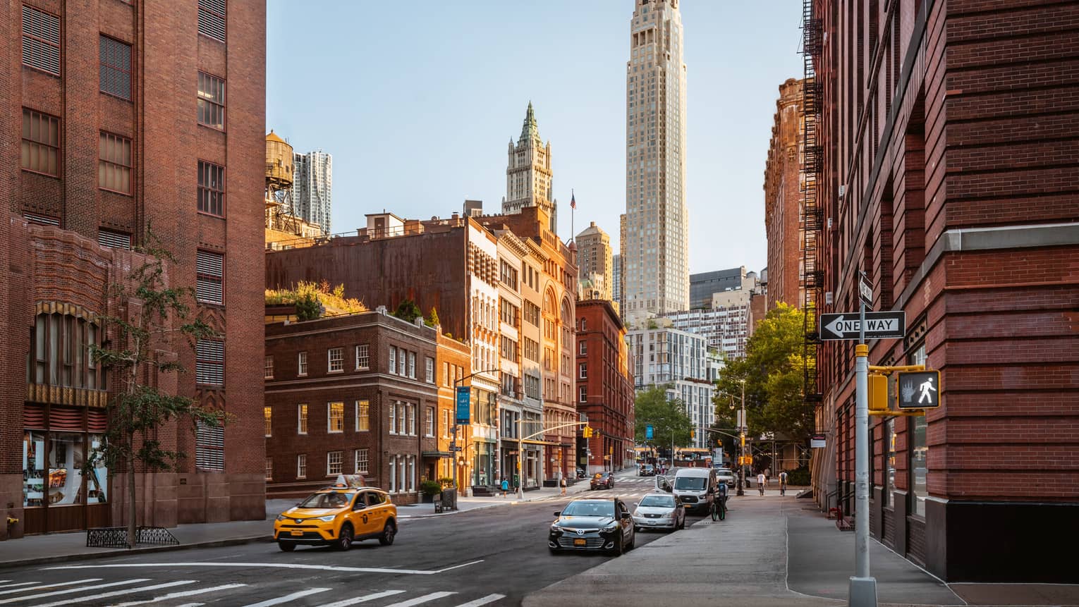 A downtown New York street with red brick buildings on either side and city towers in the background