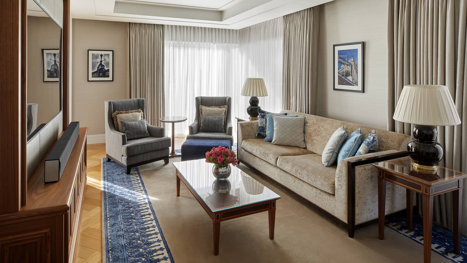 A living room with sofa, two chairs, coffee table, television, side table and large window.