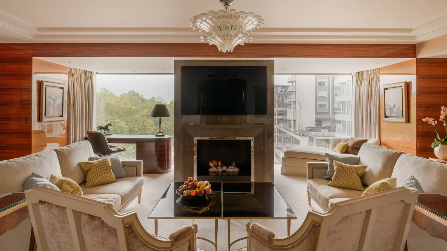 Elegant living room of Presidential Suite, with two sofas and two arm chairs, fireplace, TV and chandelier at Four Seasons Hotel London