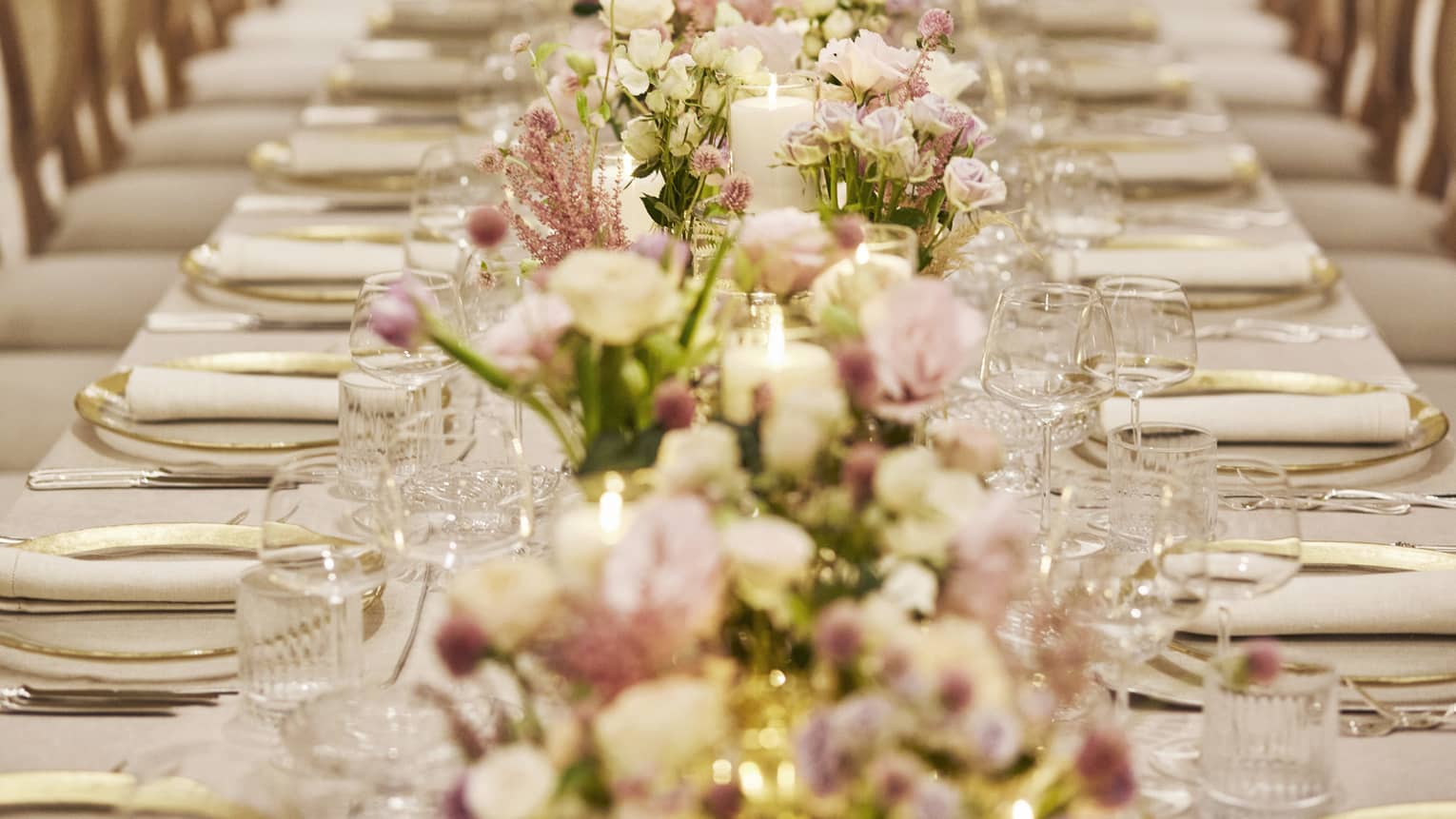 Elegantly set formal dining table with pink and white floral arrangements down centre