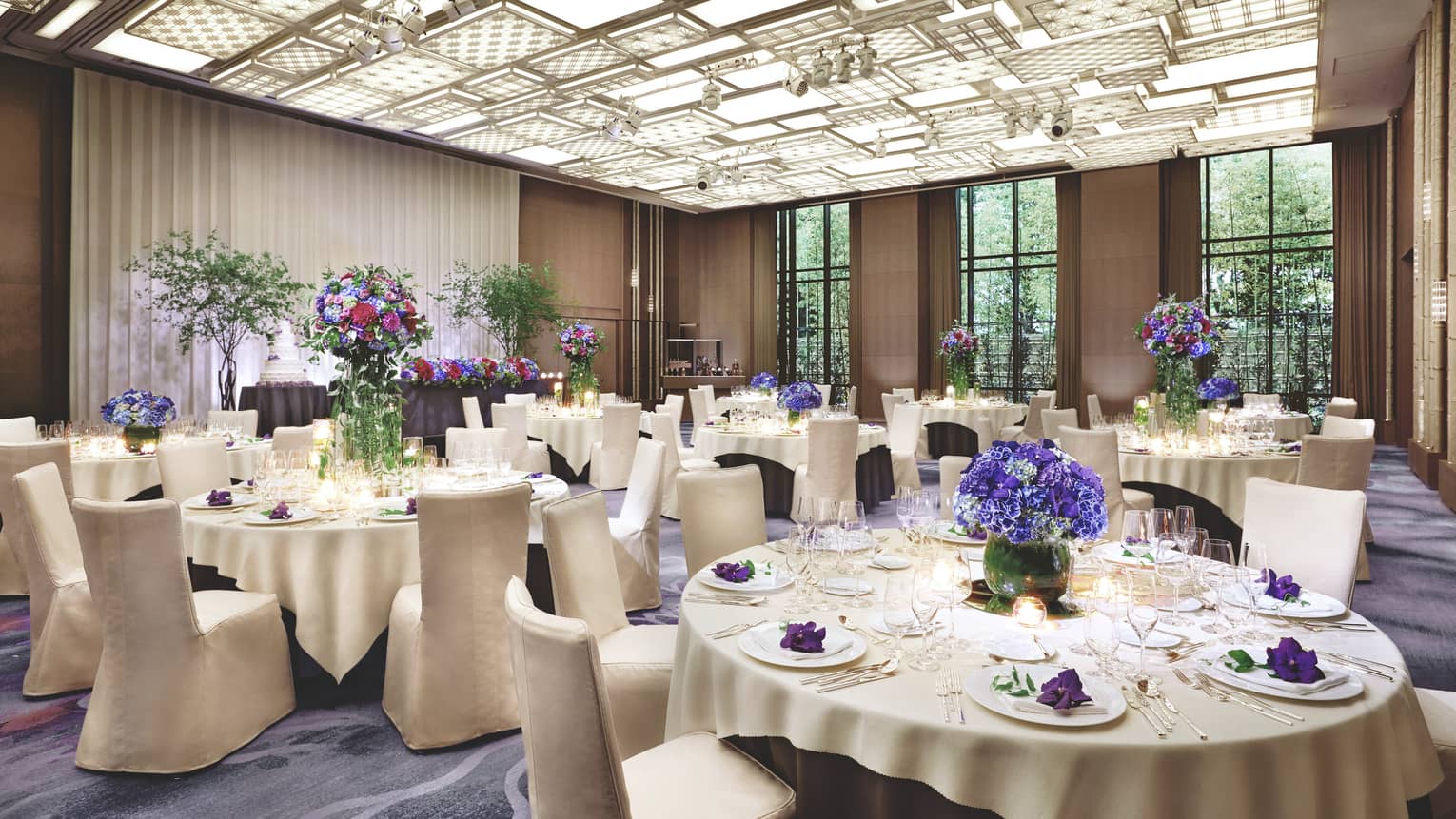 Ballroom event with round banquet tables under patterned, panel ceiling, lights
