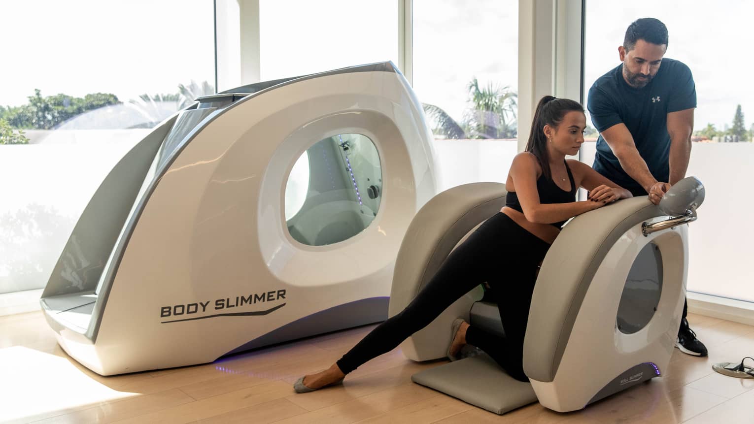 A woman in a machine with a wellness practitioner assisting her.