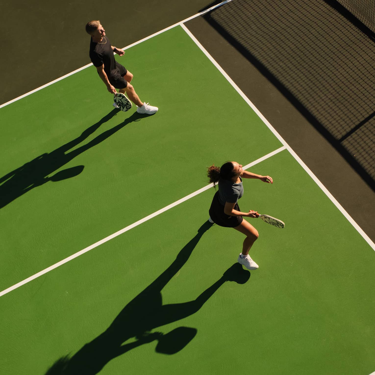 Aerial view of a man and woman playing pickleball on an outdoor court