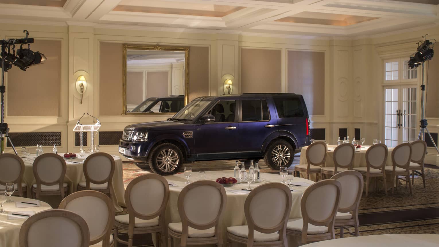 S U V car parked inside ballroom, surrounded by banquet tables and chairs 