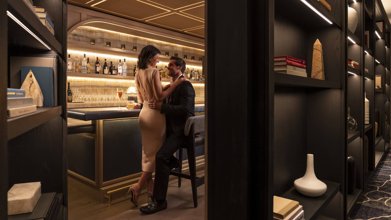 A man and woman in nice clothes sitting at a bar.