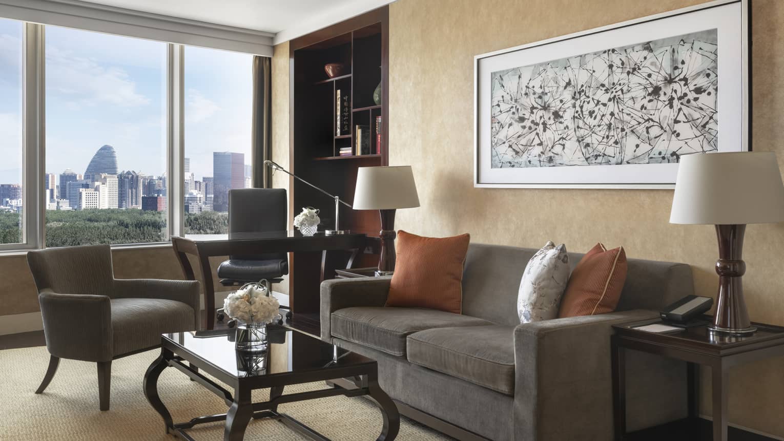 Living room with dark grey, two-seat sofa, chair, desk and chair, and window